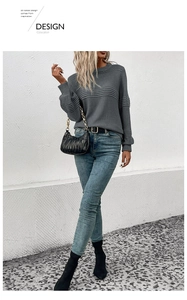 Close-up of dark grey crew neck knit sweater featuring textured ribbed cuffs and neckline detail