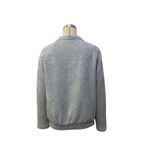 Detail eines grauen strukturierten Langarm-Sweatshirts mit geometrischem Steppmuster und Bündchen