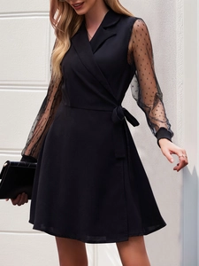 Close-up of black wrap dress featuring semi-transparent polka dot mesh sleeves and waist tie