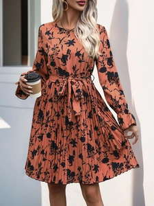 Detail of pleated hem and floral pattern on orange long sleeve drawstring waist dress