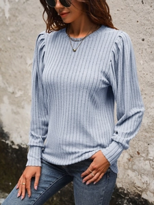 Detail of light blue ribbed knit top with stylish puff sleeves in an outdoor setting