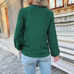 Détail du tissu à pois verts foncés et des finitions en dentelle sur le col de la blouse