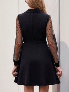 Detail of elegant black dress showing long sheer mesh sleeves with textured polka dots