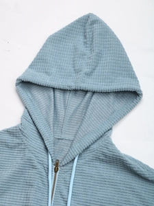 Detailaufnahme von hellblauem Cord-Kapuzenpullover mit Metallreißverschluss und Waffelstruktur