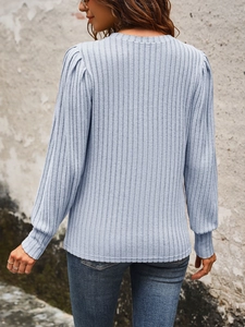 Detail of light blue ribbed knit top showing soft texture and subtle puff sleeve design