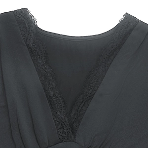 Détail du col en V avec bordure en dentelle florale noire sur une robe élégante