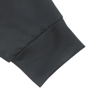 Gros plan du poignet côtelé d'une robe noire montrant l'élasticité et la texture du tissu