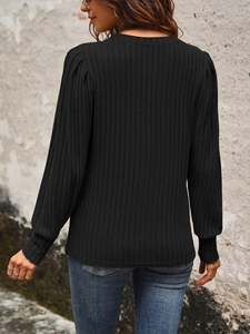 Detail of black ribbed knit top featuring subtle puff sleeves and long elastic cuffs