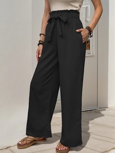Detail of high waist paperbag trousers in black with adjustable tie belt and loose fit