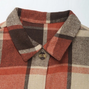 Macro detail of plaid sleeveless cardigan featuring amber button and wool texture