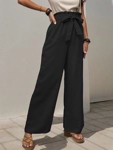 Detail view of black high waist paperbag trousers with adjustable bow belt and textured fabric