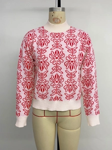 Detailed view of pink Fair Isle sweater with red floral patterns and ribbed knit cuffs