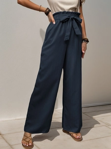 Detail of high waisted wide leg trousers featuring a ruffled elastic waist and a tie-up belt