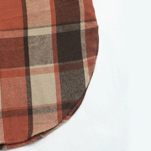 Close-up of curved hem and stitching on orange plaid sleeveless cardigan vest