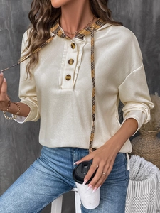 Detailed waffle texture of beige hoodie featuring brown plaid drawstrings and button placket
