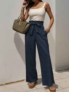 Detail of high waisted paperbag pants with a bow tie and elegant wide leg fit
