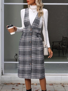 Detail of grey plaid pinafore dress set with white turtleneck and front button accents
