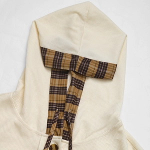 Detail of waffle knit fabric texture and plaid patchwork lining with amber buttons