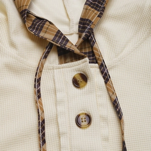 Detail of waffle knit fabric with plaid drawstring and amber buttons on hoodie