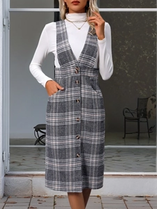 Detail of grey plaid pinafore dress featuring V-neckline and button-up front design