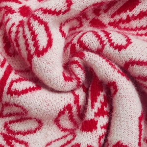 Detailed macro view of soft pink and red jacquard knitted fabric with plush texture