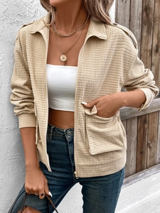 Detail of beige textured corduroy cardigan featuring large utility pockets and metal zipper