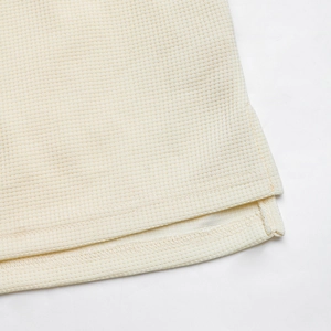 Detailed macro view of off-white waffle knit fabric hem and split side seam finish