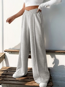 Detail of grey wide leg trousers featuring a unique cross V-waist and front seam stitching