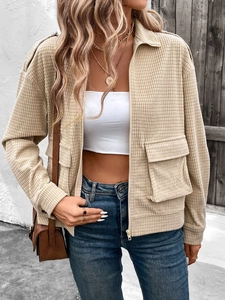 Close-up of beige textured corduroy zip-up jacket with pockets in street style