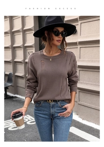 Detail showing the distressed taupe knit sweater texture and ripped hem on the round neck top
