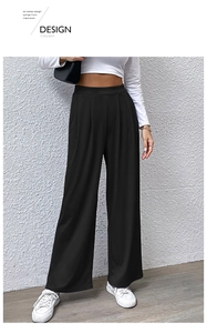 Close-up of high-waist black wide-leg trousers featuring elegant pleated waist details