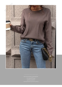 Close-up of distressed knit fabric with irregular holes on a brown crewneck sweater