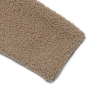 Close-up detail of soft tan polar fleece fabric with premium stitched edge texture