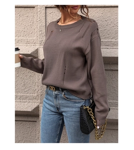 Detail shot of the distressed hole knit pattern and crew neck of the brown casual sweater