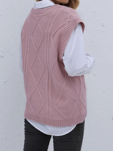 Détail du gilet en tricot rose montrant le motif de losanges et de torsades texturés