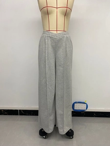 Detailed view of grey high-waisted wide-leg trousers featuring unique V-cross pleated waistband