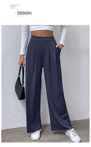 Detail view of high-waisted wide-leg navy trousers featuring pleated waist and side pockets
