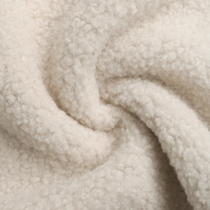 Close-up of soft beige sherpa fleece fabric showing warm texture and fluffy curly fibers