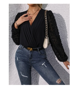 Close-up of black V-neck bodysuit featuring textured sheer sleeves and elegant pleat details