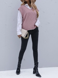 Détail d'un gilet en tricot rose à losanges porté avec une chemise blanche chic
