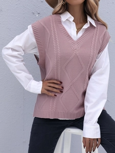 Détail d'un gilet en tricot rose à col en V montrant la texture torsadée sur chemise