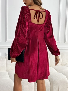 Detail of burgundy velvet dress featuring backless square neck and elegant tie-up ribbon