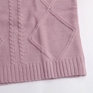Détail de la maille torsadée et de l'ourlet côtelé sur ce gilet rose à col en V