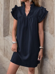 Close-up of pleated navy blue dress showing ruffle sleeves and high neck V-neckline texture
