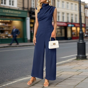 Detail of navy blue sleeveless jumpsuit with cowl neck and wide-leg cut on a sunny street