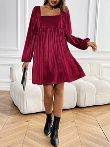 Detail of burgundy velvet pleated dress with square neck and long sleeves in studio