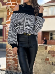 Detail eines Rollkragenpullovers mit Cut-Out-Schultern und schwarz-weißem Fischgrätenmuster