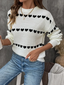 Detail shot of white knit sweater featuring black heart patterns and ribbed texture