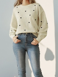 Cream crewneck knit sweater with black heart patterns paired with high-waist jeans