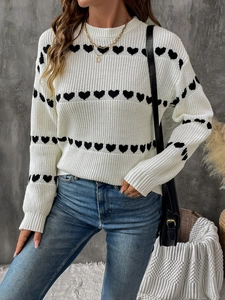 Detail of white knit sweater showing black heart jacquard pattern and ribbed cuffs